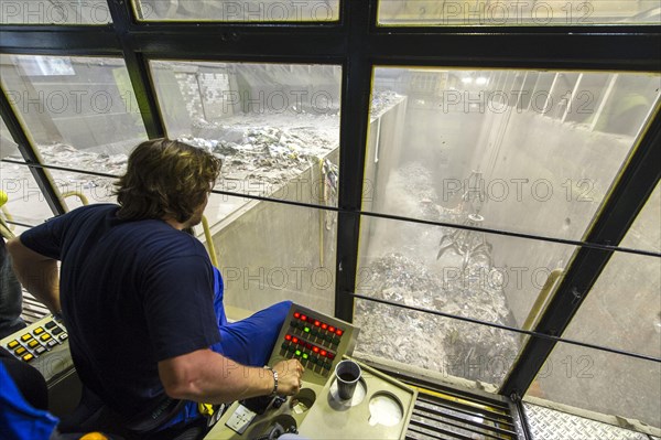 A crane operator is supervising the transport of waste to the incinerators in a waste incineration plant