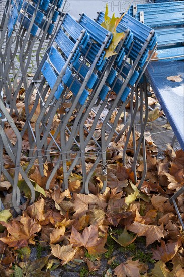 Empty tables and chairs of an outdoor restaurant in the rain with autumn leaves in the historic town centre of Cologne