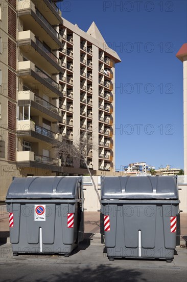 Wheeled trash cans standing in front of an apartment complex