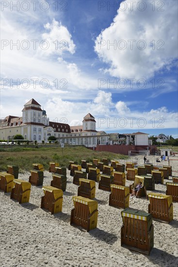 Roofed wicker beach chairs on the beach in front of the Kurhaus spa building