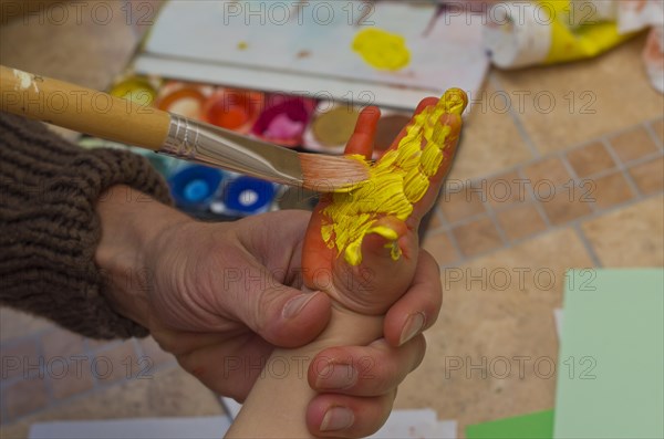 Hand of a little child getting painted with acrylic paint to create a handprint