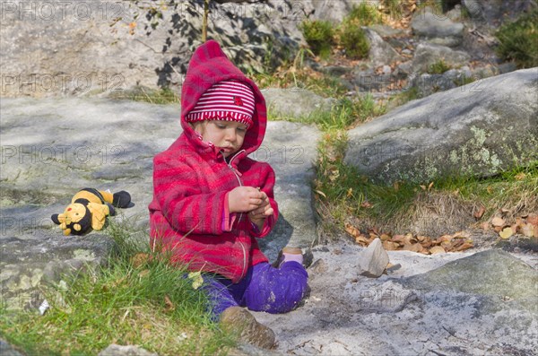 Little girl playing between rocks in the sand