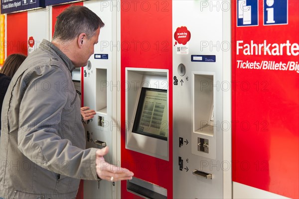 Confused man standing in front of a ticket machine