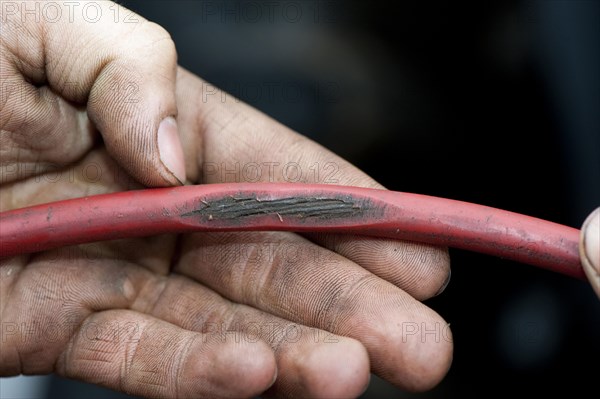 Mechanic with worn cable on tractor which could be dangerous