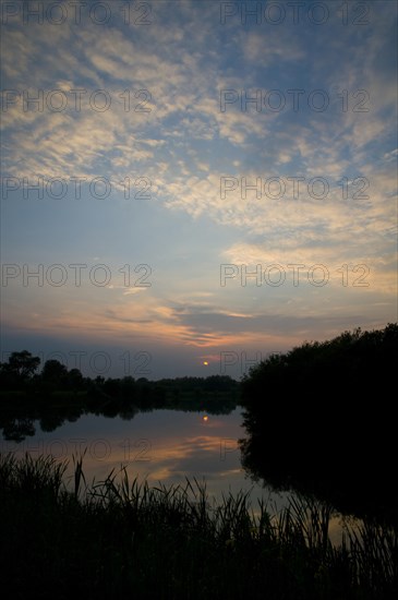 View of cirrocumulus clouds over flooded former gravel pit habitat at sunset