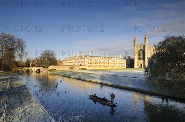 View of river with punt approaching bridge and college buildings in frost