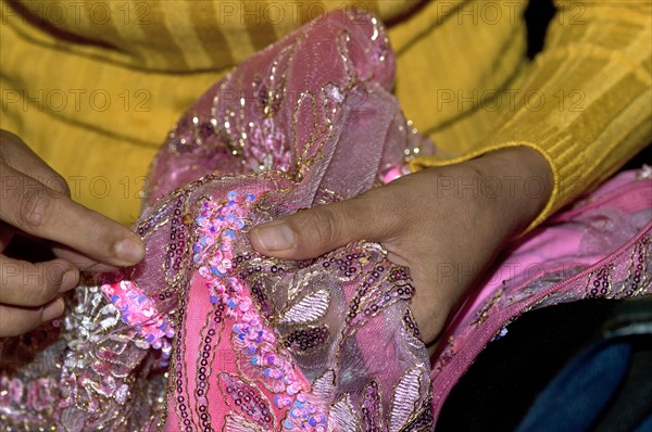 Tailor embroidering a party dress with glittering sequins