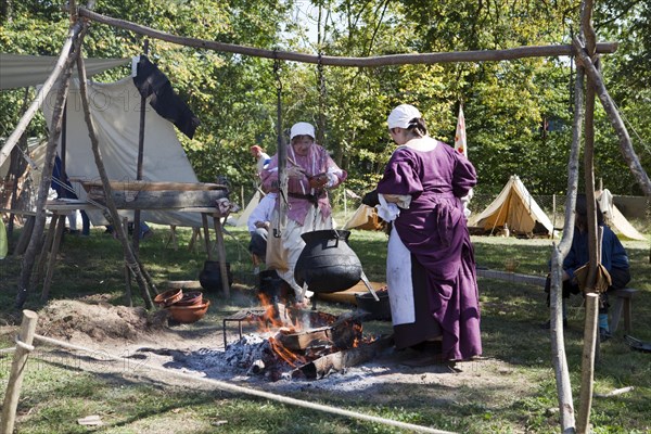 Women with a cooking pot over a campfire