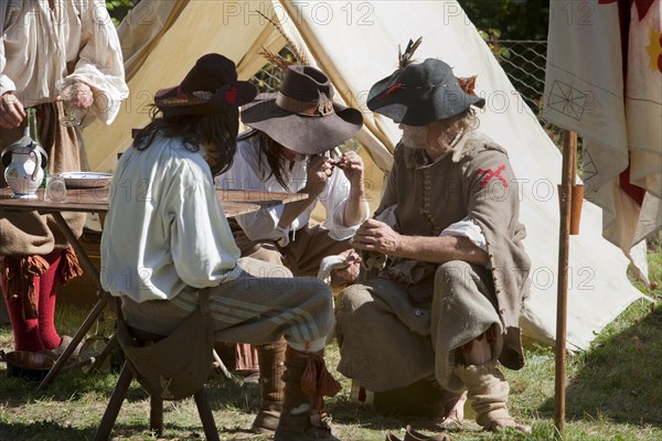 Men dressed in Medieval costumes sitting in front of a tent