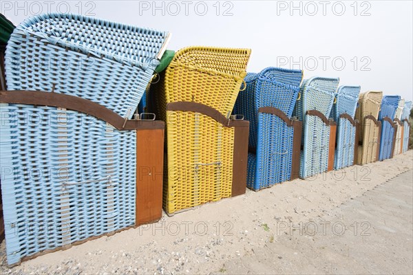 Perspective image of a row of blue and yellow roofed wicker beach chairs