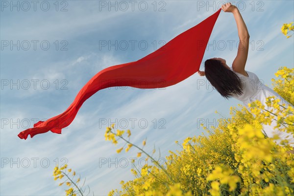 Oblique rear view of a young woman in a blooming canola field