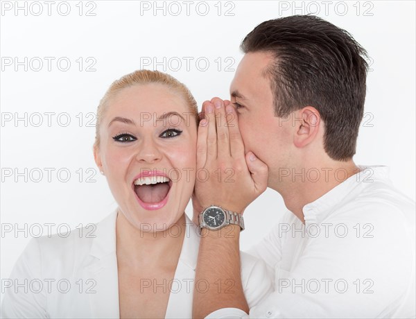 Young man whispering something into the ear of his young partner