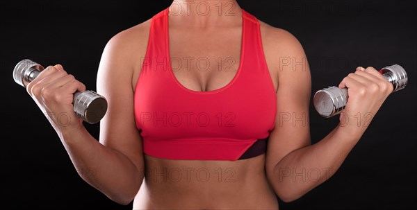 Young woman's upper body wearing a red sports bra while doing fitness training with chrome dumbbells