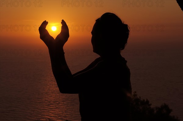 Silhouette of a woman against the sunset sky