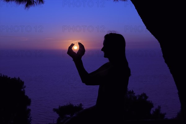 Silhouette of a woman against the sunset sky