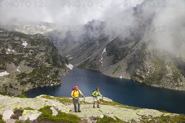 A man and a woman hiking at the Lago della Crosa mountain lake