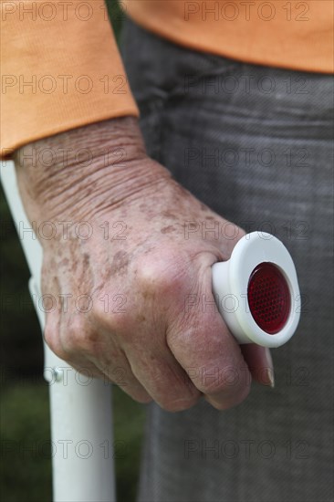 Elderly woman standing with a crutch in her hand