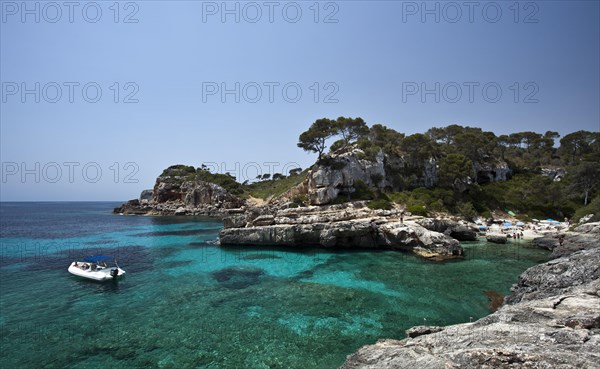 Boat in the rock-lined bay of Calo des Moro