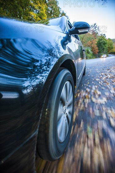 Car driving on a street covered with leaves