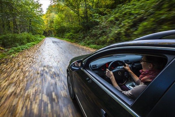 Car driving on a street covered with leaves