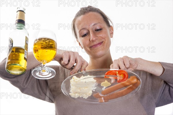 Young woman sitting at a glass table eating Frankfurter sausages with potato salad