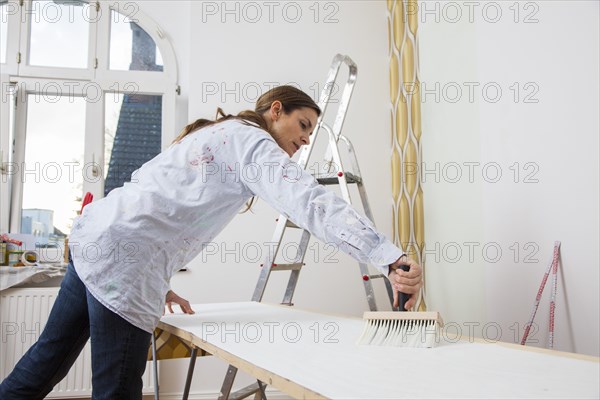 Young woman preparing wallpaper for wallpapering the walls