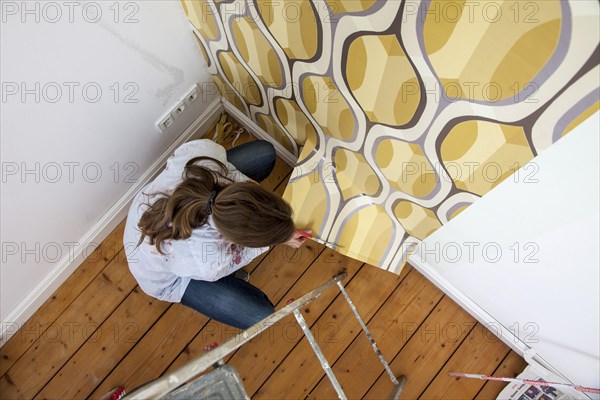 Young woman wallpapering a wall