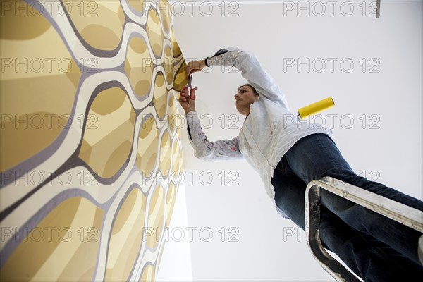 Young woman wallpapering a wall