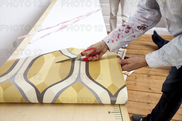 Young woman wallpapering a wall