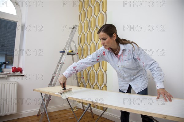 Young woman preparing wallpaper for wallpapering a wall