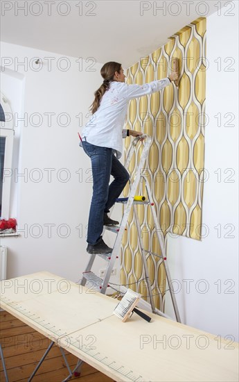 Young woman wallpapering a wall