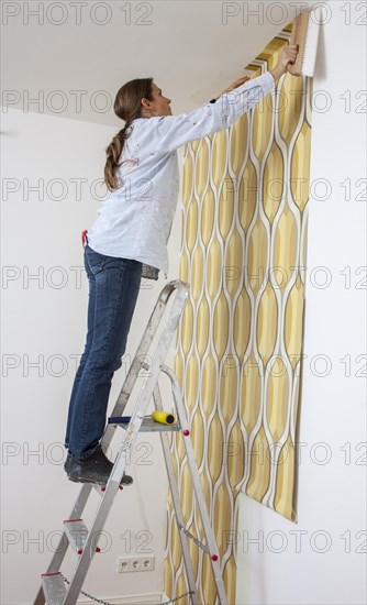 Young woman wallpapering a wall