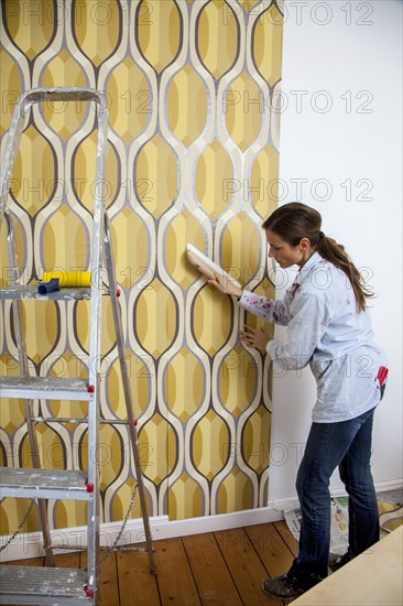 Young woman wallpapering a wall