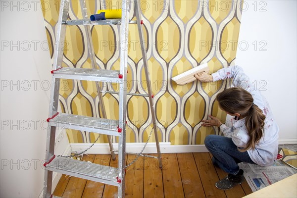 Young woman wallpapering a wall