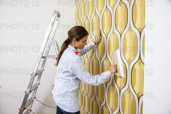 Young woman wallpapering a wall