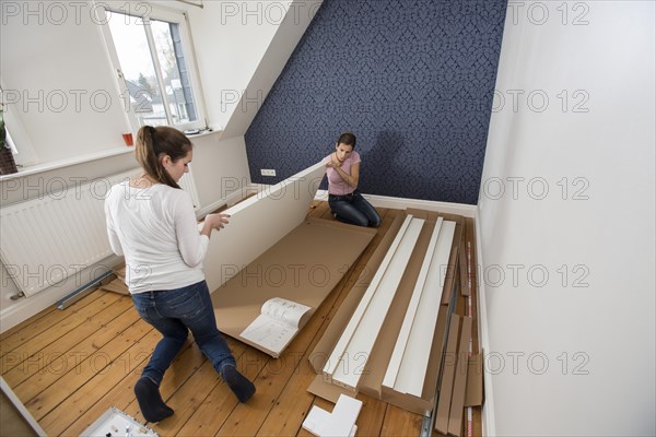 Mother and daughter working together to assemble a bed in the daughter's room