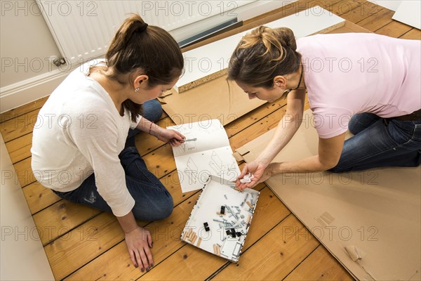 Mother and daughter working together to assemble a bed in the daughter's room