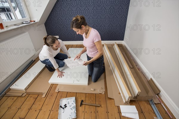 Mother and daughter working together to assemble a bed in the daughter's room