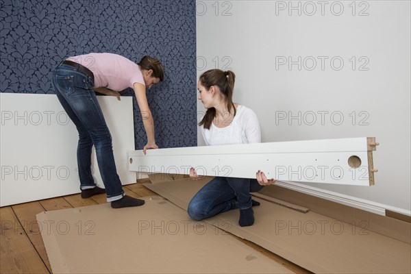 Mother and daughter working together to assemble a bed in the daughter's room