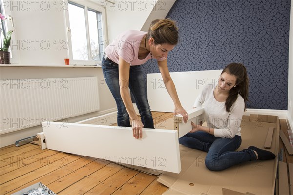 Mother and daughter working together to assemble a bed in the daughter's room