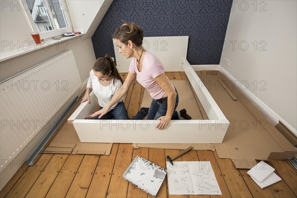 Mother and daughter working together to assemble a bed in the daughter's room