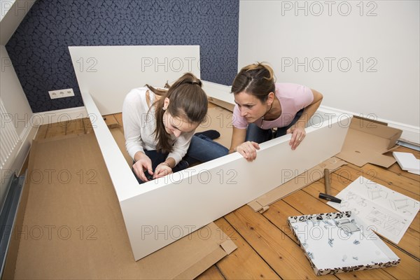 Mother and daughter working together to assemble a bed in the daughter's room