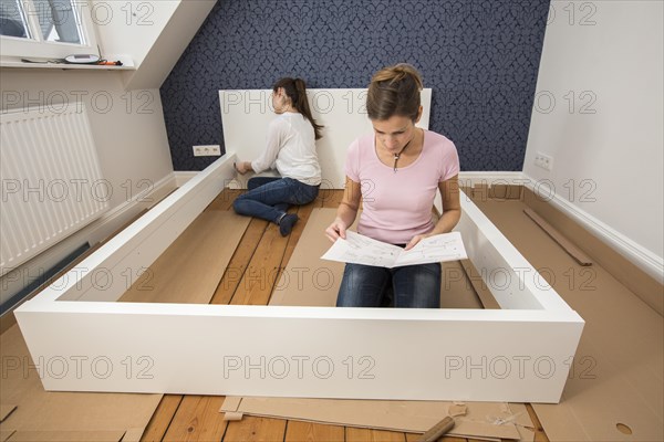 Mother and daughter working together to assemble a bed in the daughter's room