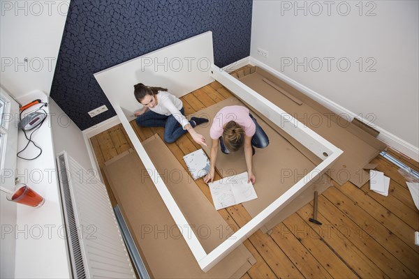 Mother and daughter working together to assemble a bed in the daughter's room