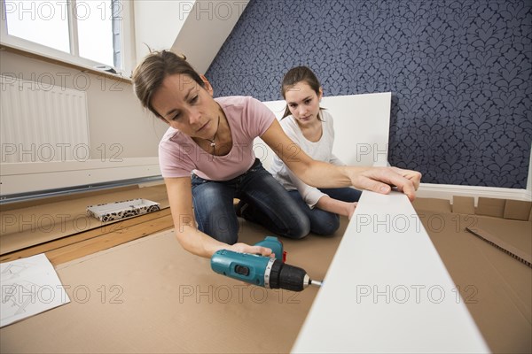 Mother and daughter working together to assemble a bed in the daughter's room