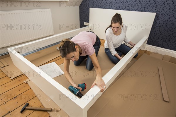 Mother and daughter working together to assemble a bed in the daughter's room