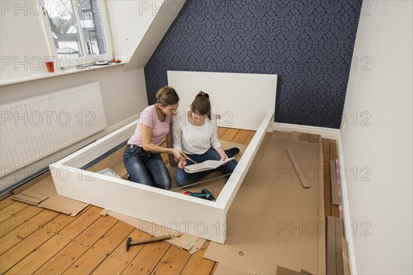 Mother and daughter working together to assemble a bed in the daughter's room