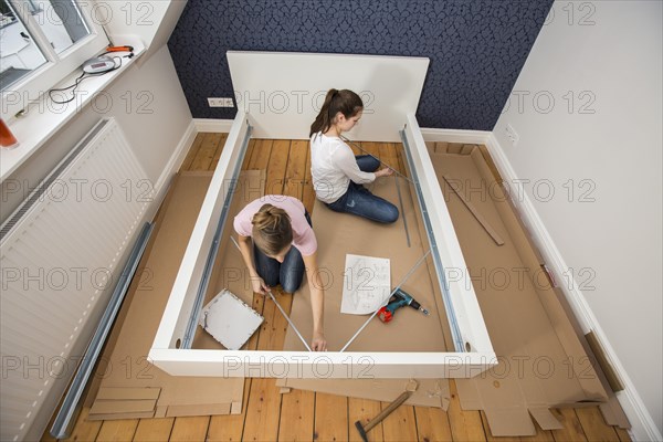 Mother and daughter working together to assemble a bed in the daughter's room