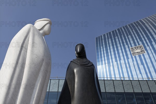 Sculpture of an Arab man and an Arab woman in front of the EMAAR building