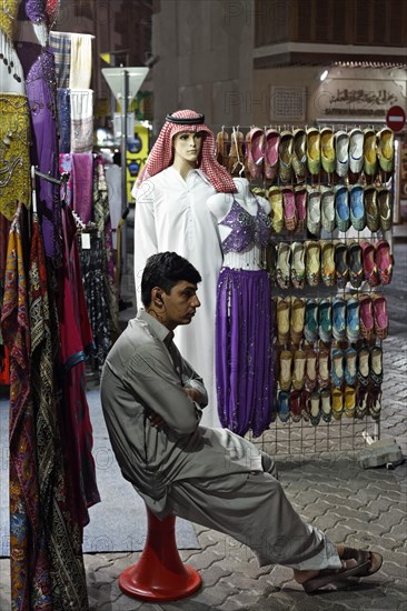 Salesman sitting bored in front of his shop